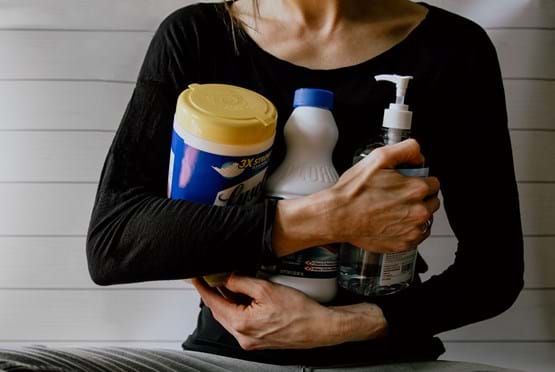 woman wearing a black shirt holding cleaning products in her arms