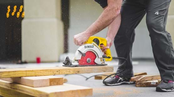 Construction worker using saw to cut wood