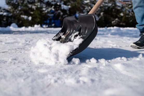 A snow shovel scoops up snow.